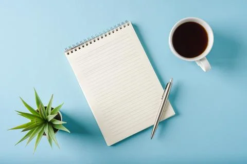 Top view of notebook, coffee and ballpoint pen on blue background Stock Photos