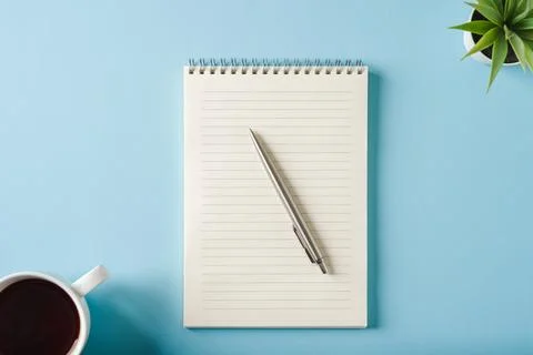 Top view of notebook, coffee and ballpoint pen on blue background Stock Photos