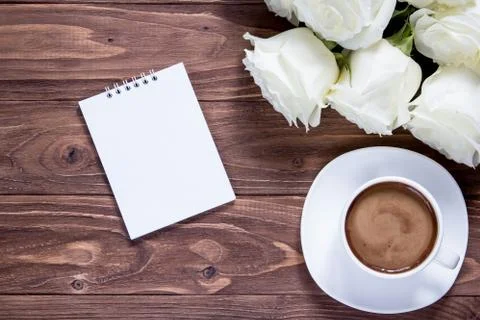 Top view on notebook, coffee cup and bouquet of roses on wooden surface Stock Photos