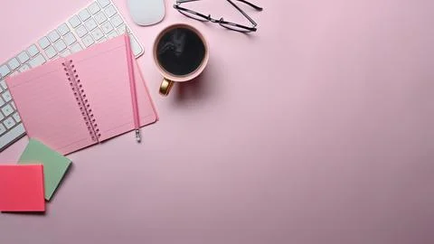 Top view notebook, coffee cup, sticky notes and glasses on pink background. Stock Photos