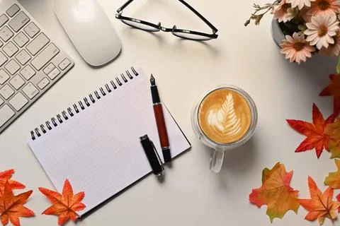 Top view notebook, coffee cup, glasses and maple leaves on white table. Stock Photos