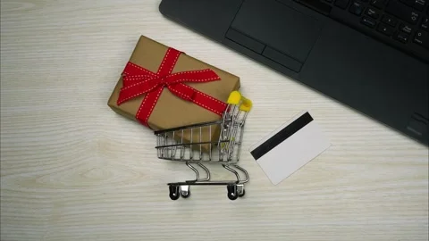 Top View of notebook, credit card and supermarket trolley with gift box. StopMo Stock Footage 257965554