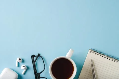 Top view of notebook, glasses, coffee and ballpoint pen on blue background Stock Photos