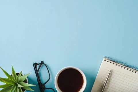 Top view of notebook, glasses, coffee and ballpoint pen on blue background Stock Photos