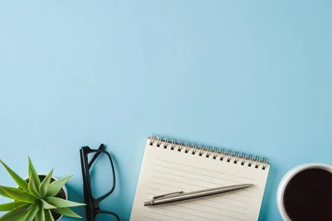 Top view of notebook, glasses, coffee and ballpoint pen on blue background Stock Photos