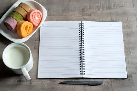 Top view of notebook, jam roll, cup of milk, pen on wooden, Business, educati Stock Photos