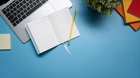 Top view notebook, laptop computer, sticky note and potted plant on blue 写真素材
