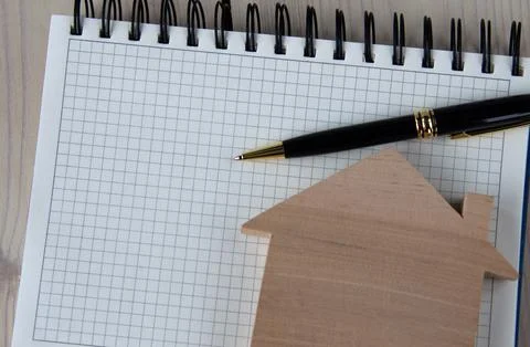 Top view of notebook, pen and wooden house. Place for recording. Stock Photos