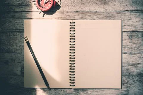 Top view of notebook with pencil and clock on wooden table background. Vint.. Stock Photos