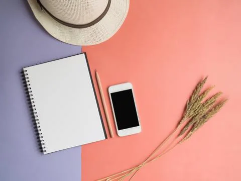 Top view of notebook, smartphone, hat, dried flower on violet purple backgrou Stock Photos