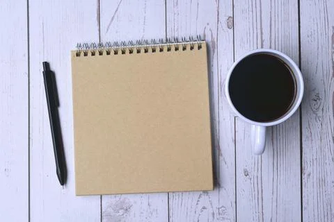 Top view of notepad and pen with cup of coffee on wooden desk Stock Photos