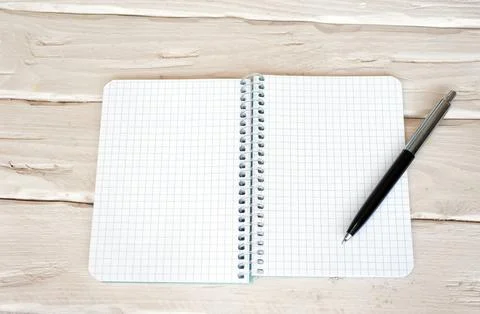 Top view notepad with a blank page in a cage with a black push button pen. .. Stock Photos