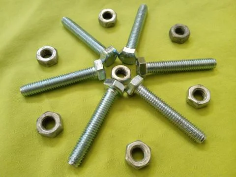 Top view of nuts and bolts on a yellow surface Stock Photos