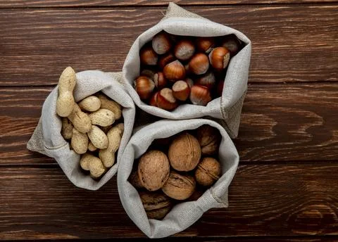 Top view of nuts in sacks walnuts peanuts and hazelnuts in shell on wooden .. Stock Photos