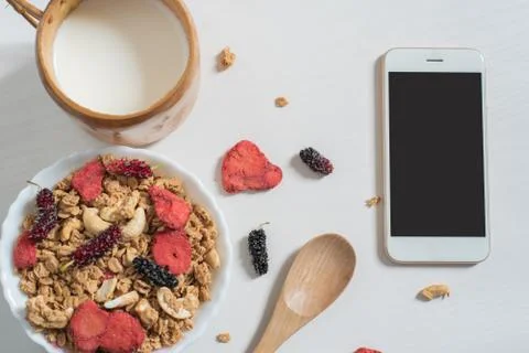 Top view of oat flakes with strawberry, mulberry, almond , milk and cellphone Stock Photos