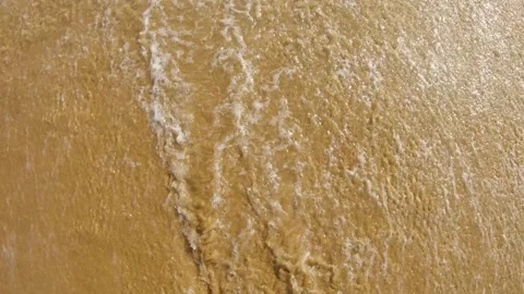 Top view of ocean waves continuously washing over a golden sandy beach. Видео 307416263