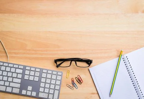 Top view of office desk with computer keyboard, eye glasses and notebook Stock Photos