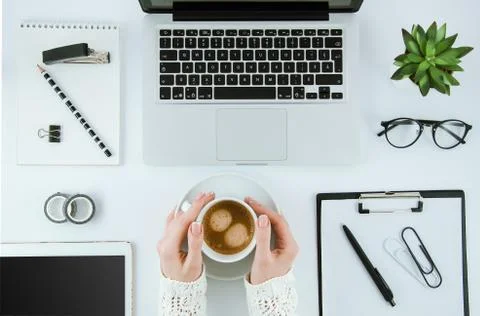 Top view office desk. Workspace with girl's hands, laptop, notepad, clipboard Stock Photos