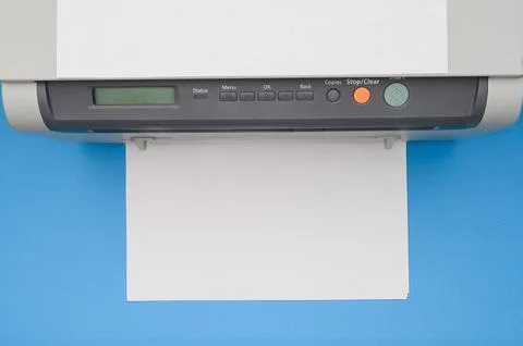 Top view of an office printer and a blank sheet of paper on a blue background. Stock Photos