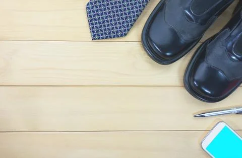 Top view office table with necktie, work shoes, smart phone and pen for busin Stock Photos