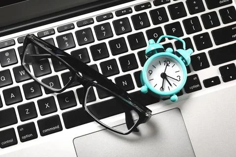 Top view of office workplace desk table with laptop, supplies, and alarm clock Stock Photos