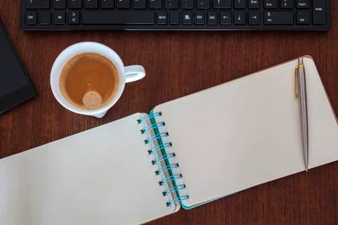 Top view of office workspace with blank notebook, computer, coffee cup and sm Stock Photos