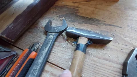 Top view of old hand tools including a hammer, wrench, and pliers on a wooden ba Stock Footage 335644434