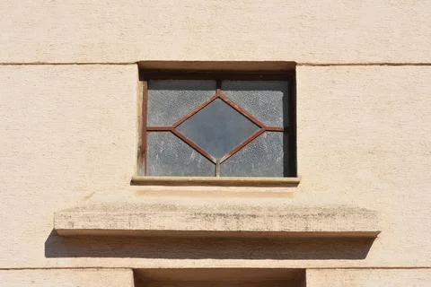 Top view of old small window with diamond pattern glass on a building facade Stock Photos