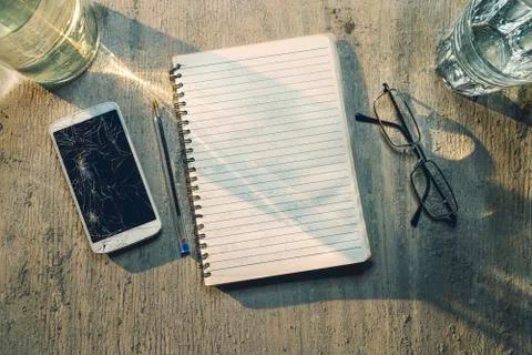 Top view of an old table with mobile, pad, pencil and glasses Stock Photos