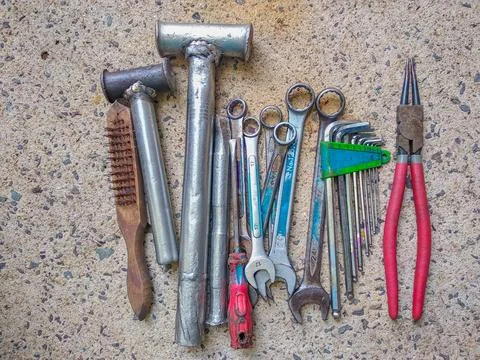Top view of old workshop tools, welded hammers, and wrenches on concrete floor Stock Photos