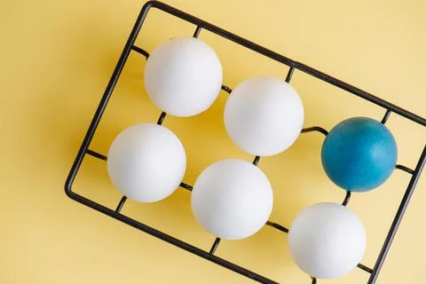TOp view of one blue egg and five regular ones on a metal egg holder over yellow Stock Photos