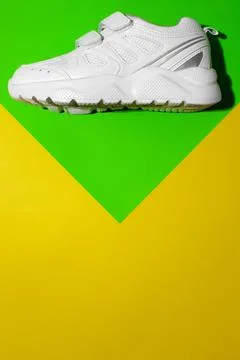 Top view one white running shoes on top on a geometric paper green and yellow Stock Photos