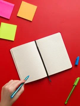 Top view of an open blank red notebook in the center, colored reminders in hi Stock Photos
