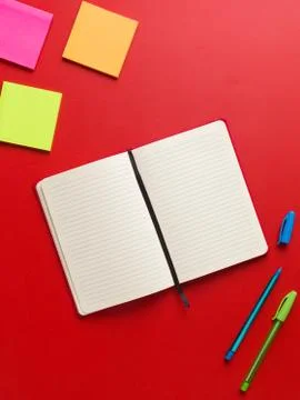 Top view of an open blank red notebook in the center, colored reminders in hi Stock Photos