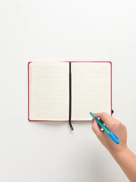 Top view of an open blank red notebook in the center, and a female hand holdi Stock Photos