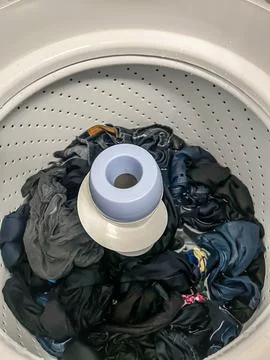 Top view of an open laundry washing machine with dark colored cloths sorted. Foto stock