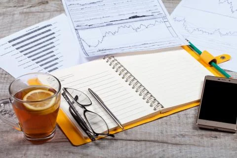 Top view of open notebook, glasses, a cup of tea, pen and smartphone on a wooden 스톡 사진