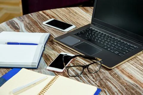 Top view open notebook, laptop and glasses on the office table. Stock Photos