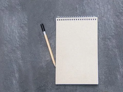 Top view of a open notebook with recycled paper with pencil on a slate back.. Stock Photos
