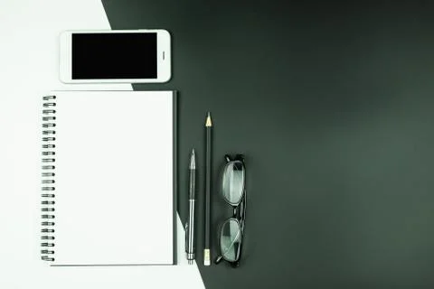 Top view of open notebook with smart phone and stationery on black and white  Stock Photos