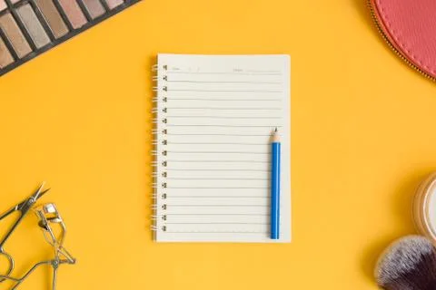 Top view of an open  notepad and blue pencil surrounded by cosmetic items on  Stock Photos