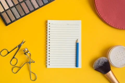 Top view of an open  notepad and blue pencil surrounded by cosmetic items on  Stock Photos