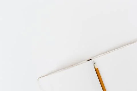 Top view of an open notepad with a pencil on a white table background Stock Photos