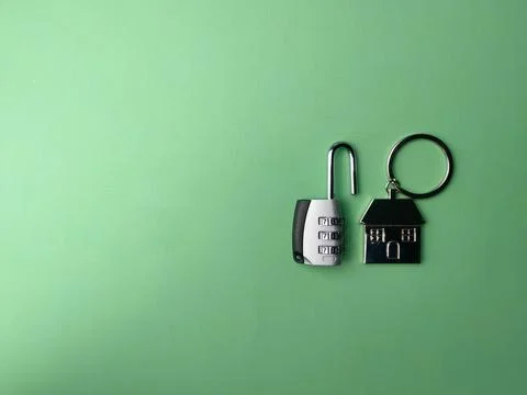 Top view open padlock and house keychain on a green background with copy sp.. Stock Photos