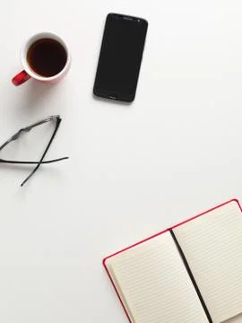 Top view of an open red notebook, a red cup of coffee, a cell phone and glass Stock Photos