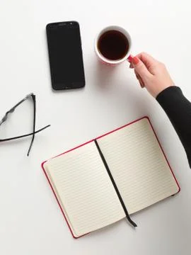 Top view of an open red notebook, a female hand holding a red cup of coffee, Stock Photos