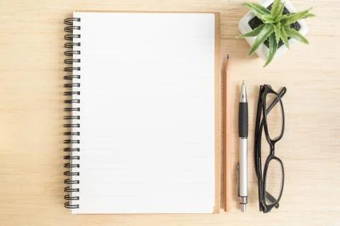Top view of open spiral notebook with brown pencil, pen, black eye glasses an Stock Photos
