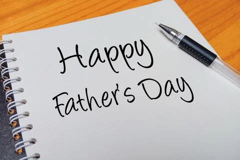 Top view of an open spiral notebook with Happy Father's Day handwritten tex.. Stock Photos