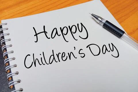 Top view of an open spiral notebook with Happy Children's Day handwritten t.. Stock Photos