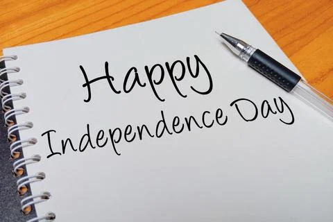 Top view of an open spiral notebook with Happy Independence Day handwritten.. Stock Photos